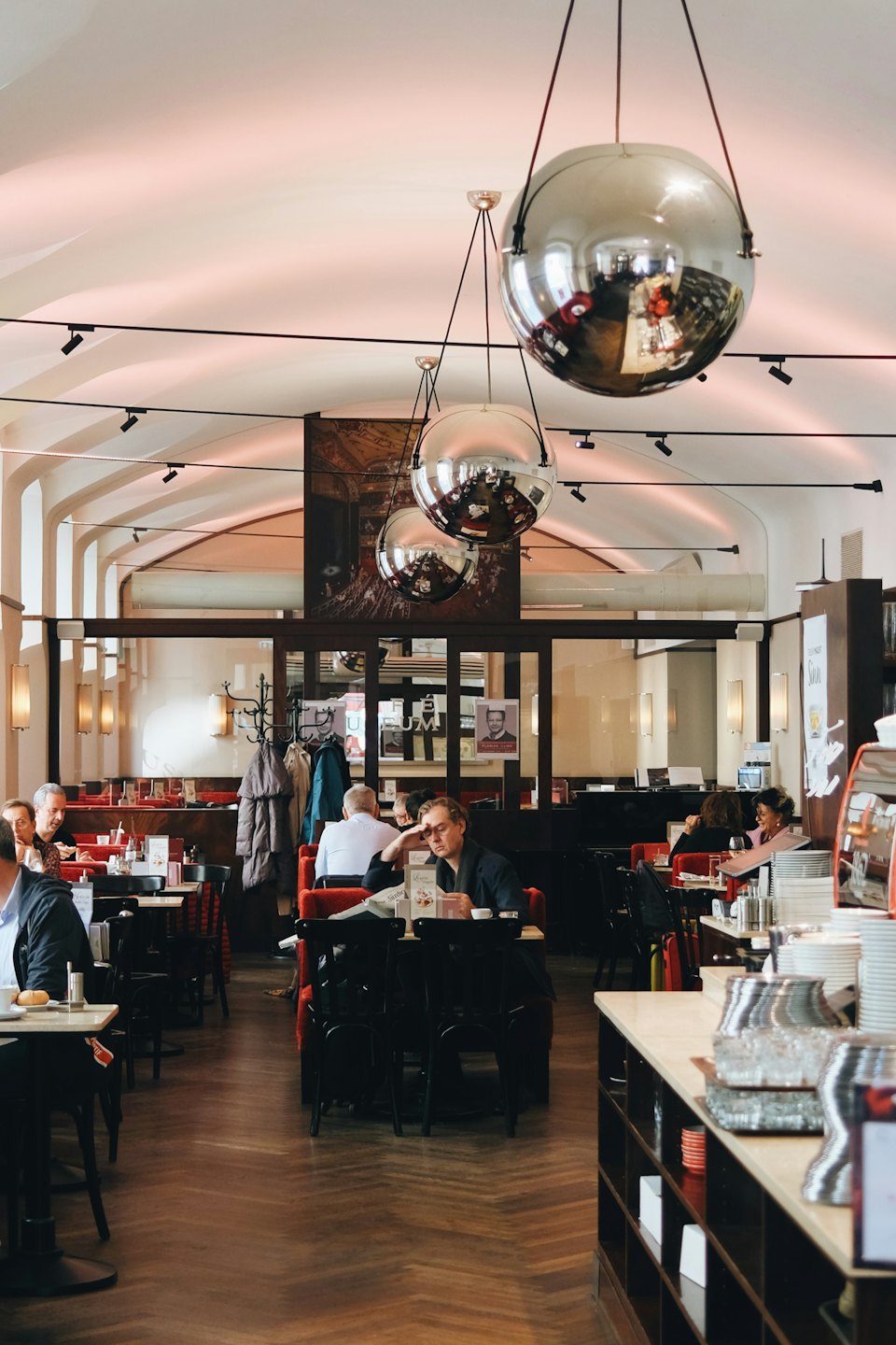 Patrons socialize while dining inside a spacious European style restaurant.